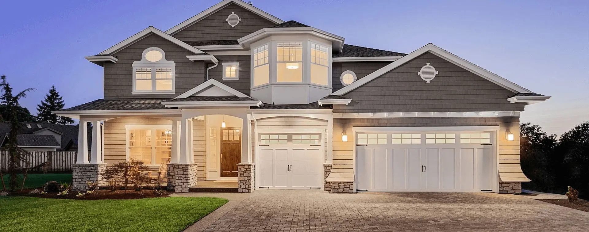 A large house with two cars parked in front of it.